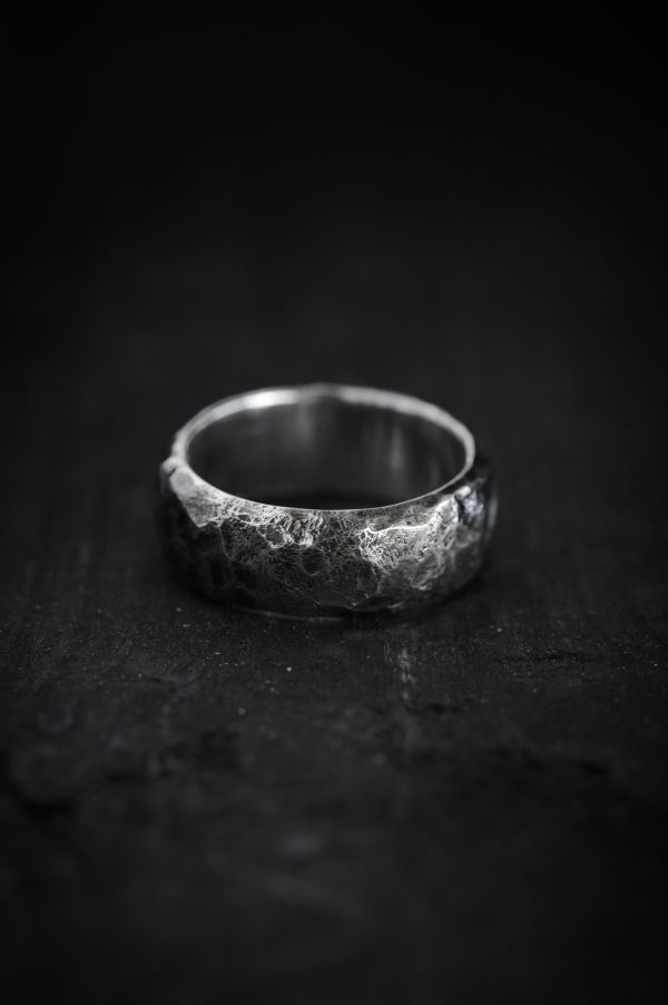 Photo of a hammered silver ring on a black background.