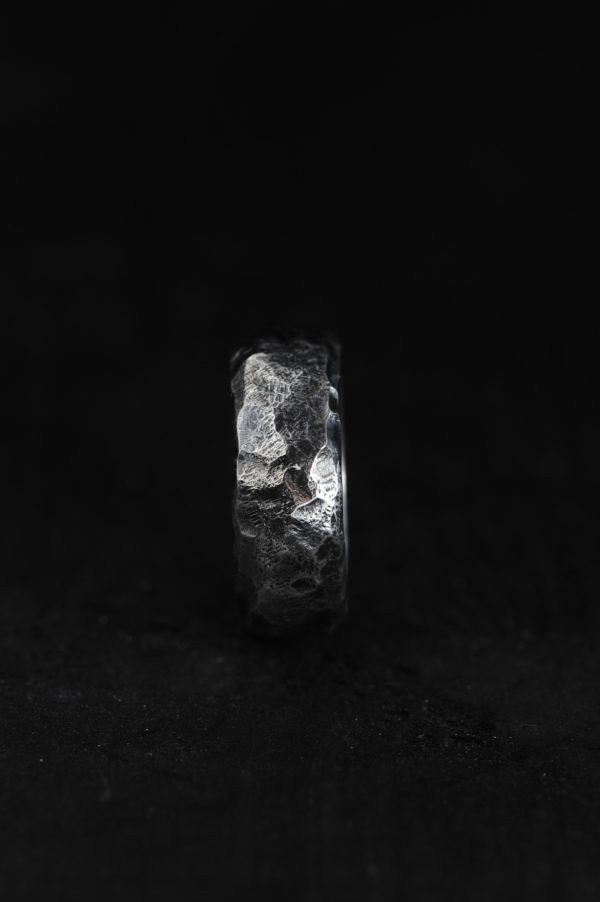 Photo of a hammered silver ring on a black background.