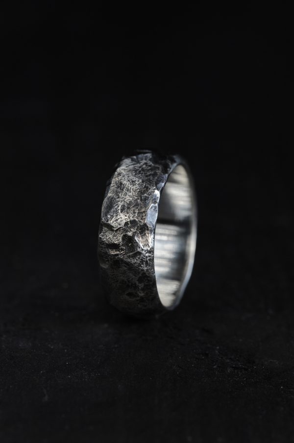 Picture of a hammered silver ring on a black background.