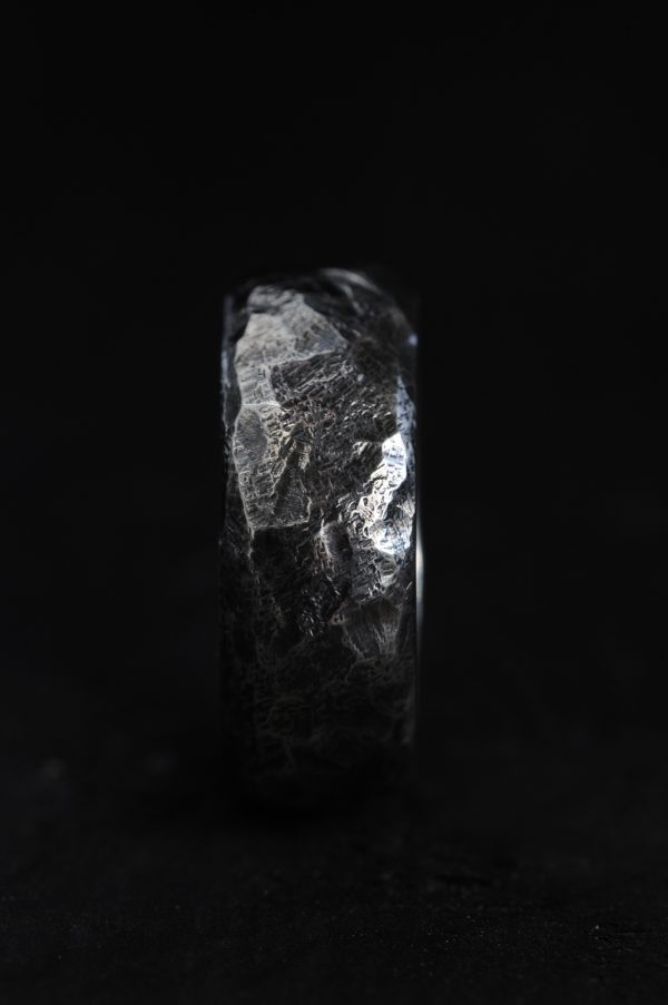 Picture of a hammered silver ring on a black background.